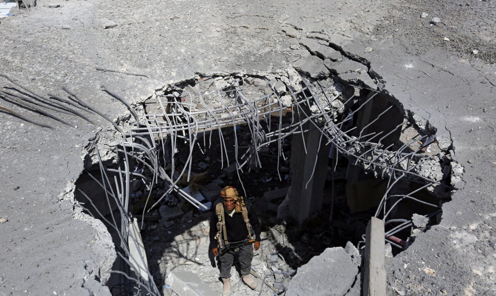 Un miembro del grupo rebelde de los hutíes mira desde un agujero en un edificio que resultó alcanzado en un nuevo ataque aéreo de la coalición liderada por Arabia Saudí en Saná (Yemen), hoy, 17 de septiembre de 2015. EFE/Yahya Arhab
