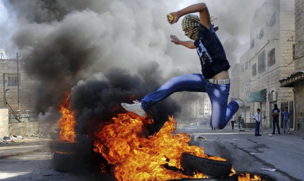 Un palestino se enfrenta a la policía israelí en Hebrón, Cisjordania, después de que Israel autorizara la entrada de visitantes judíos en la mezquita Al Aqsa, situada en territorio ocupado en 1967. EFE/Abed Al Haslhamoun