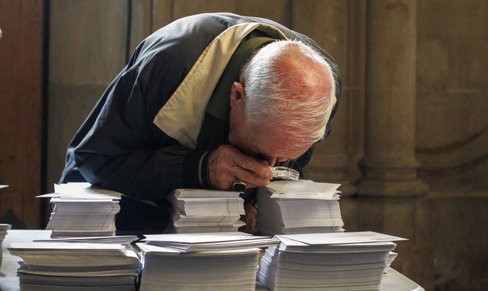 Una persoma observa con una lupa las papeletas de los diferentes partidos que concurren a las elecciones al Parlament. EFE/ Quique García