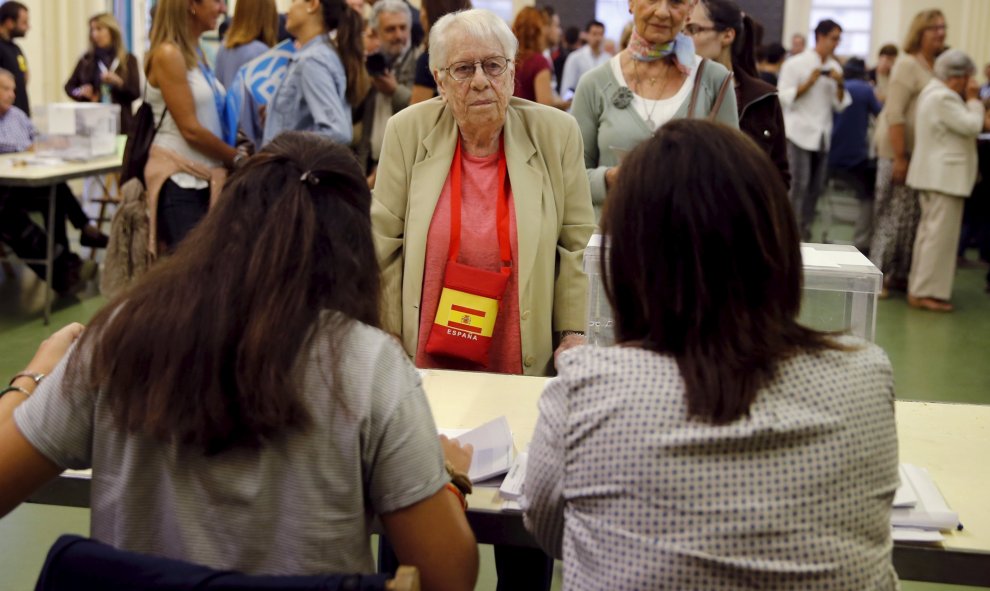 Una mujer con un bolso con los colores de la bandera española deposita su voto en un colegio electoral en Barcelona. REUTERS/Andrea Comas