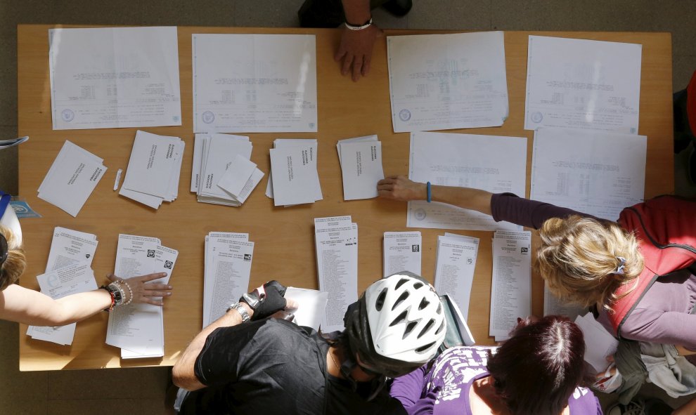 Varias personas escogen su papeleta para las elecciones al Parlamente de este 27-S en una mesa de un colegio electoral de Barcelona. REUTERS/Albert Gea