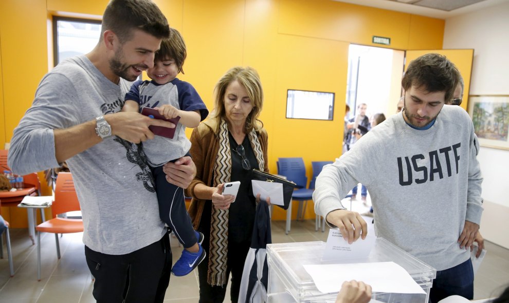 El jugador del FC Barcelona Gerard Pique, con su hijo Milan en brazos, vota en su colegio electoral en Sant Just Desvern, en Barcelona. REUTERS/Albert Gea