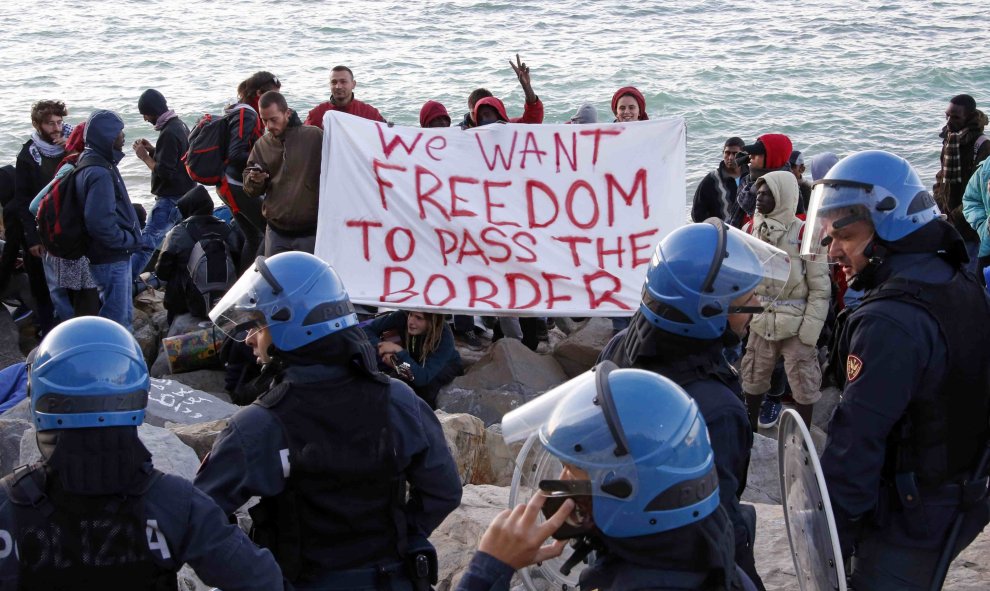 Activistas y emigrantes sostienen una pancarta que dice "Queremos libertad para cruzar la frontera" al enfrentarse con la policía italiana en el mar Mediterráneo entre Ventimiglia, Italia y Menton, Francia. REUTERS / Eric Gaillard