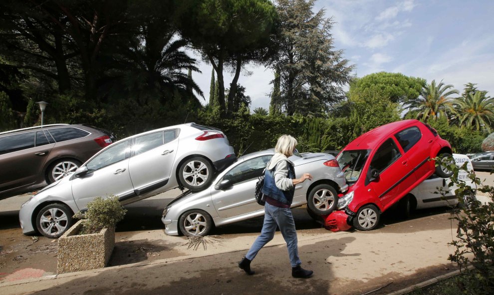 Una mujer pasa al lado de coches que han quedado colocados uno encima de otro como consecuencia de las inundaciones en Mandelieu-La Napoule, Francia, 5 de octubre de 2015. REUTERS/Jean-Paul Pelissier