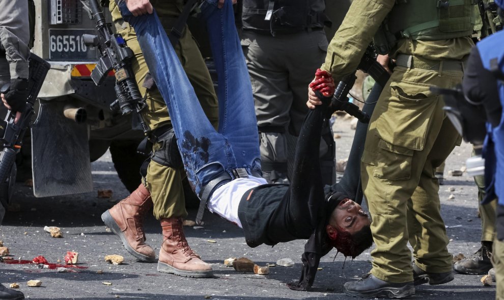 Dos soldados israelíes transportan a un palestino, herido en un enfrentamiento con soldados del Ejército en el puesto militar de Beit El, cerca de Ramala, en el territorio palestino ocupado de Cisjordania, Palestina. EFE/Str