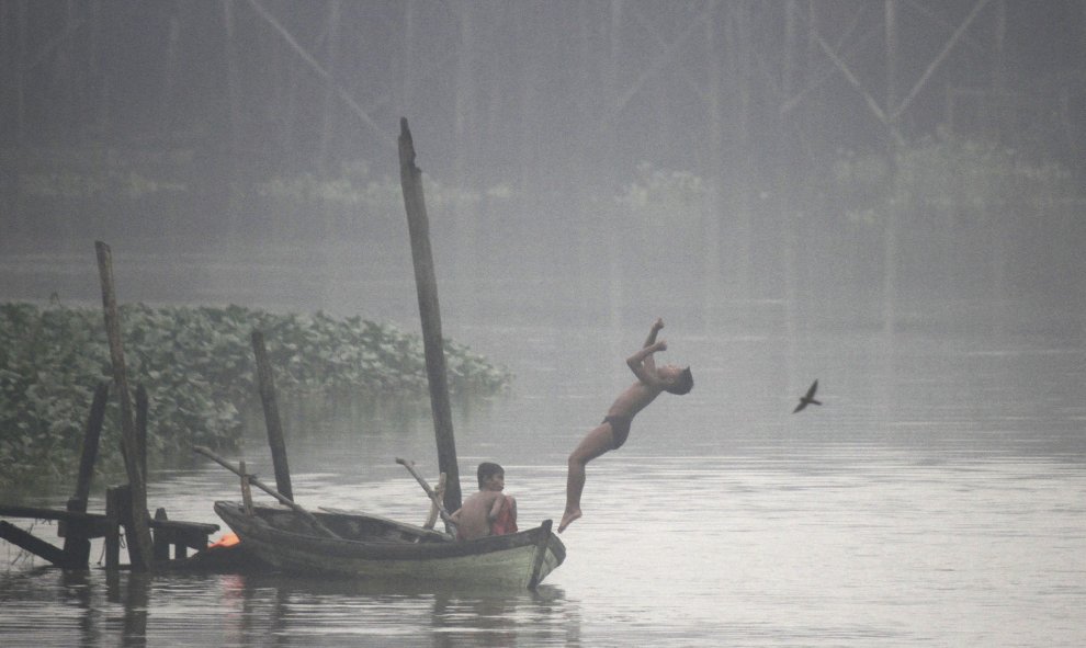 Un niño indonesio salta desde un bote al río Siak en medio de una nube de humo en Pekanbaru, en la provincia de Riau (Indonesia). EFE/Rony Muharrman