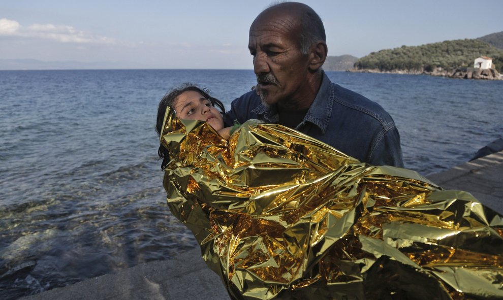 Un lugareño lleva en brazos a una niña siria tras llegar la pequeña en lancha a la isla de Lesbos (Grecia) desde Turquía, hoy, 9 de octubre de 2015. EFE/Yannis Kolesidis