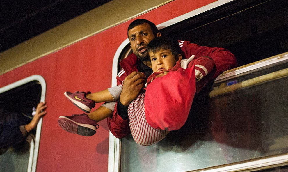 Un hombre sostiene a un niño en un tren rumbo a Serbia desde la frontera entre Macedonia y Grecia. Macedonia es un país clave en la ruta de migración de los Balcanes hacia la Unión Europea.- ROBERT ATANASOVSKI (AFP)