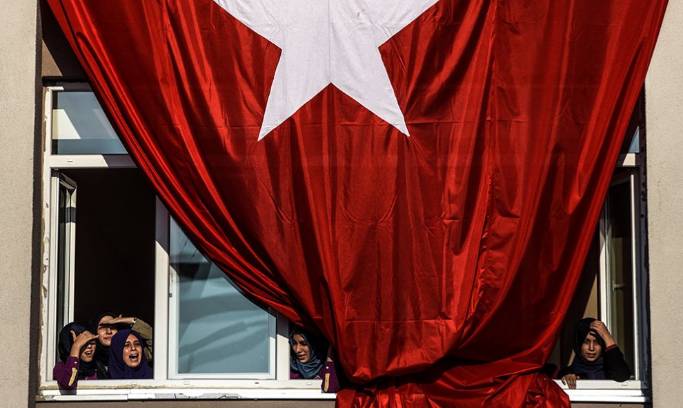 Estudiantes junto a una bandera turca gigante mientras esperan el discurso del primer ministro Ahmet Davutoglu.- OZAN KOSE (AFP