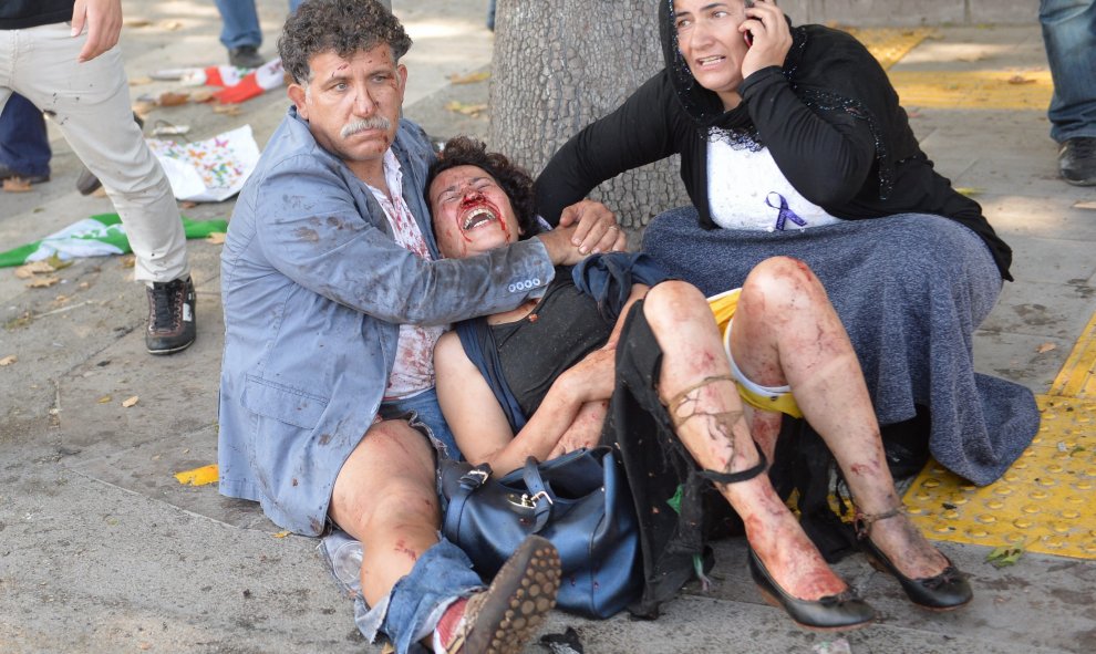 Una persona trata de ayudar a dos heridos por los atentados en Ankara. EFE/EPA/STR