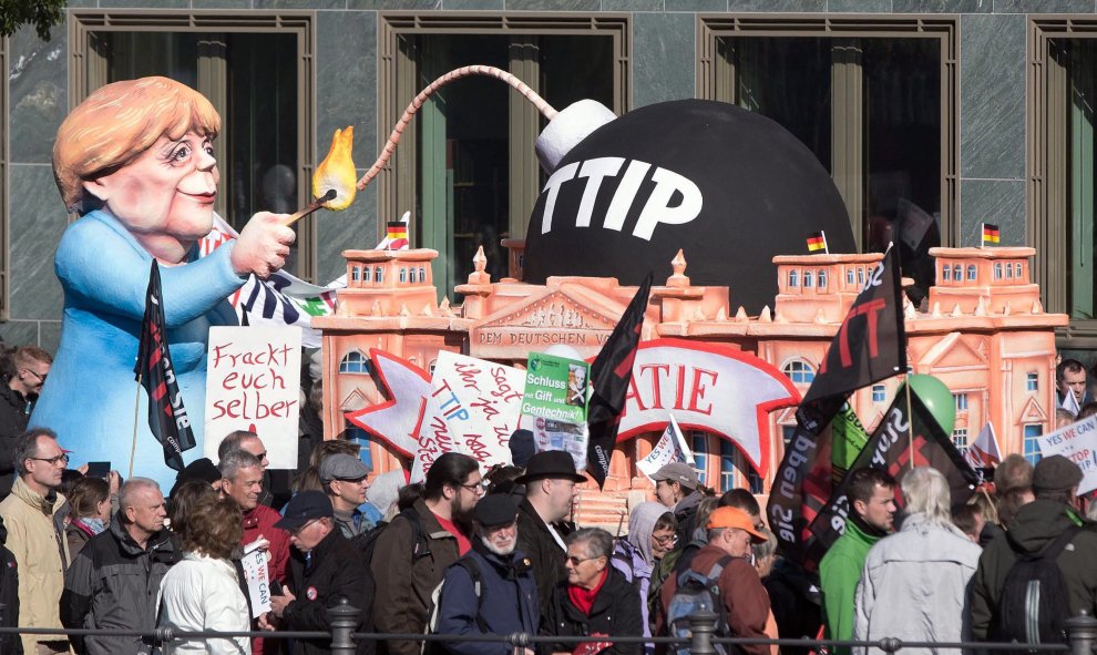Un muñeco que representa a la canciller alemana, Angela Merkel, encendiendo 'la bomba TTIP', en la manifestación de Berlín contra el acuerdo comercial que negocia la UE con EEUU. EFE / EPA / JOERG CARSTENSEN