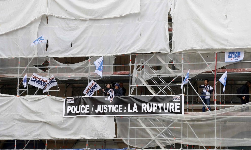 Los miembros de la Policía francesa colocan una pancarta en un andamio durante su protesta ante el Ministerio de Justicia en París por la falta de recursos. REUTERS / Jacky Naegelen