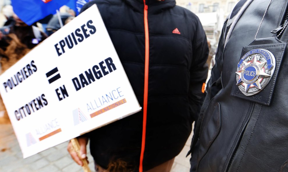 Dos agentes de la Policía francesa, en la manifestación ante el Ministerio de Justicia, en París, uno de ellos sujeta una pancarta que, en francés, dice: "Policías exhaustos0 ciudadanos en peligro". REUTERS / Jacky Naegelen