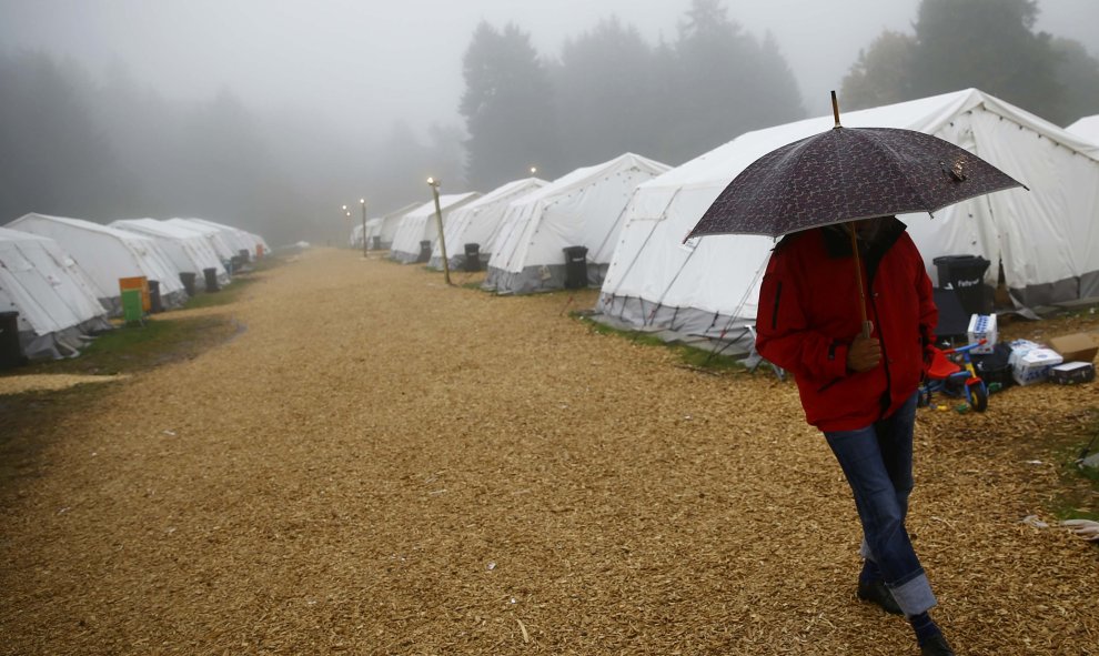 Un refugiado camina bajjo la lluvia en el campamento temporal de Schwarzenborn (Alemania). REUTERS/Kai Pfaffenbach