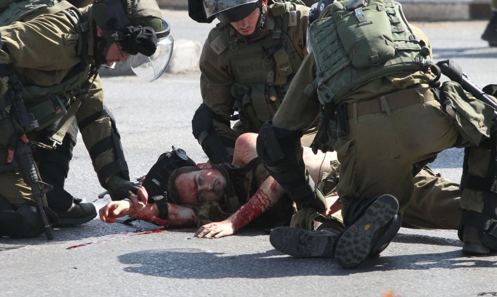 Las fuerzas de seguridad israelíes atienden a un soldado herido apuñalado por un palestino en la entrada de Hebrón, Cisjordania. AFP/ HAZEM BADER