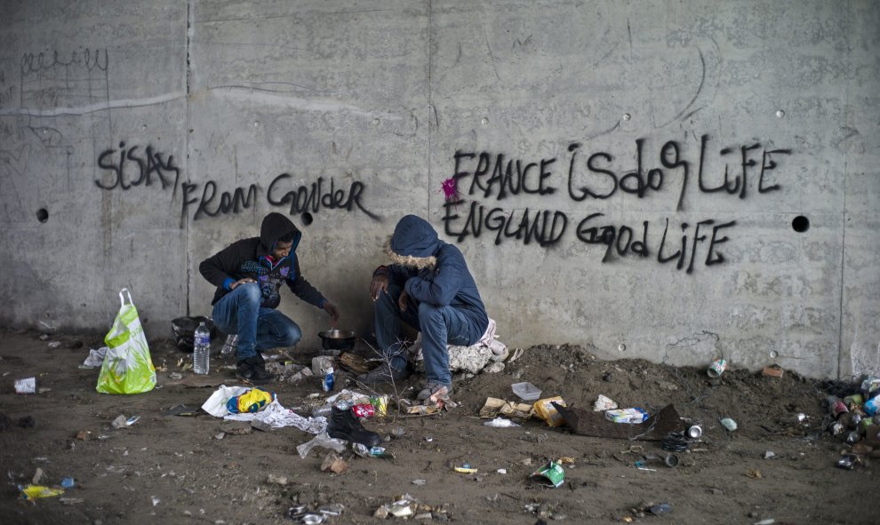 Dos refugiados eritreos cocinan bajo un puente cerca del campamento "La Jungla", en las afueras de Calais, Francia, hoy 16 de octubre de 2015. Más de 3.000 personas se alojan actualmente en el campamento. EFE/Yoan Valat