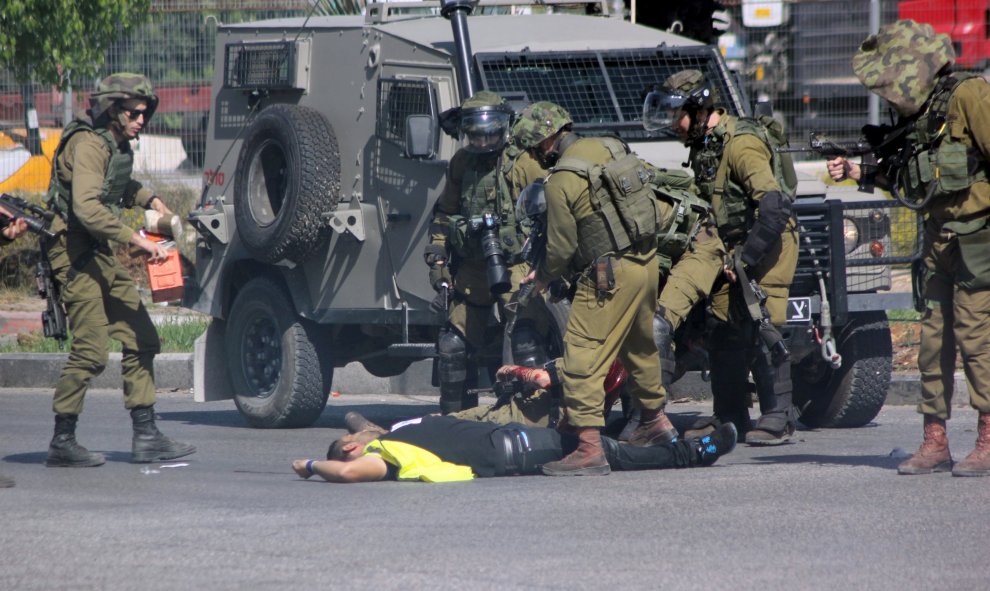 Un atacante palestino, vestido de periodista, apuñala a un soldado israelí antes de caer fulminado por los disparos del Ejército hebreo cerca de la ciudad de Hebrón, en Cisjordania.- REUTERS / Jameel Salhab