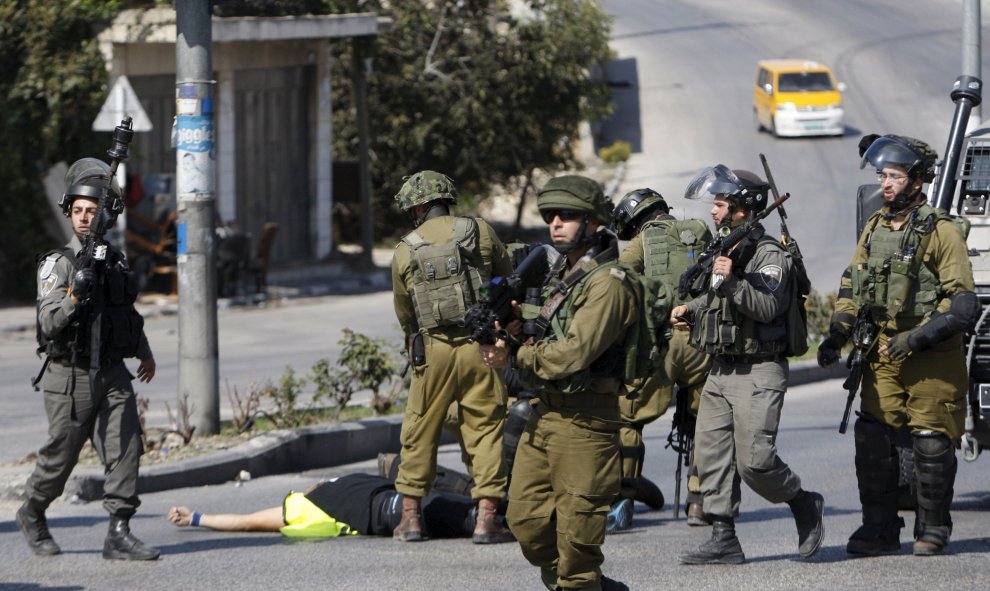 Soldados israelíes, alrededor del atacante palestino abatido por sus disparos, en Hebrón, Cisjodania.- REUTERS/Jameel Salhab