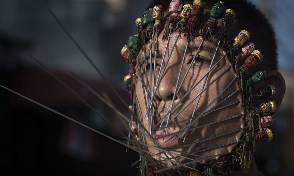 Un devoto del chino del Santuario Jui Tui tiene el rostro perforado por varillas metálicas durante una procesión durante el Festival anual Vegetariano en la ciudad sureña tailandesa de Phuket. AFP / Nicolas ASFOURI