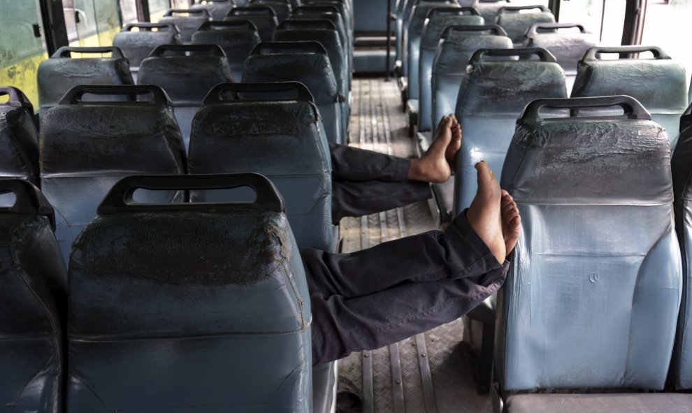 Dos conductores se echan una siesta en un autobús que permanece fuera de servicio con motivo del cese de actividades por las protestas contra la supuesta profanación de una copia del libro sagrado sij, en Amritsar (India). EFE/Raminder Pal Singh