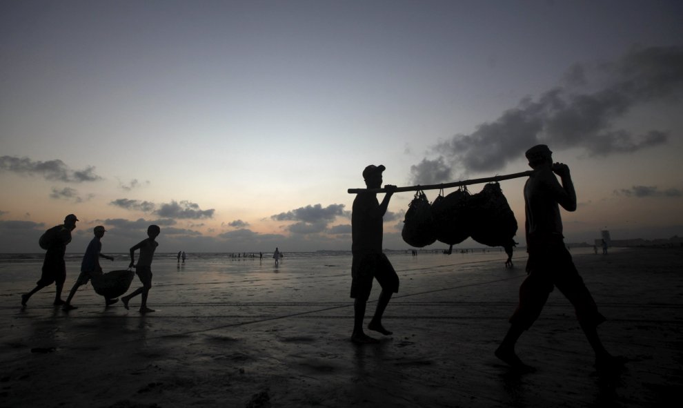 Pescadores llevan su pesca del día pasando por la playa Clifton, en su camino a casa, en Karachi, Pakistán, 19 de octubre de 2015. REUTERS / Athar Hussain