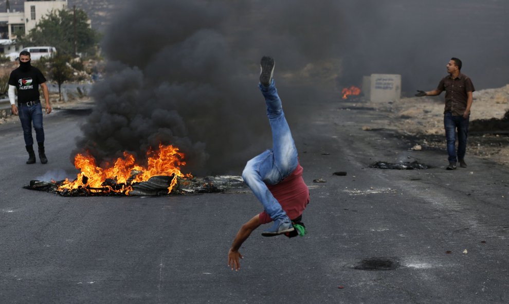 Un manifestante palestino se burla de los guardias israelíes en la frontera durante los enfrentamientos cerca del asentamiento judío de Beit El, al norte de Ramallahon. AFP PHOTO / ABBAS MOMANI