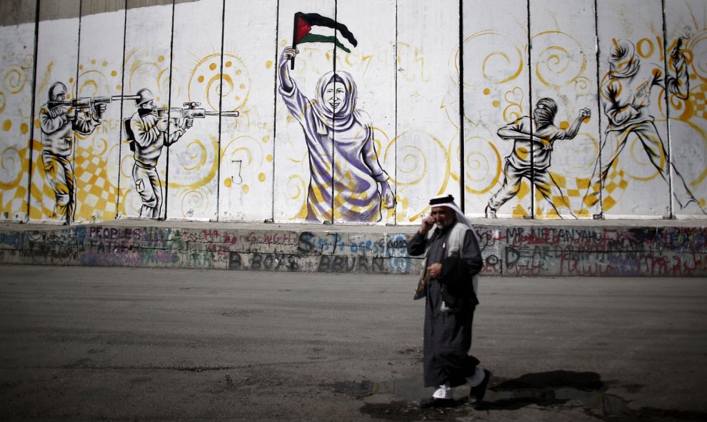 Un palestino camina en una calle donde se ve un graffiti polémico sobre la separación de Israel en un muro en la ciudad cisjordana de Belén, el 22 de octubre de 2015. AFP/THOMAS COEX