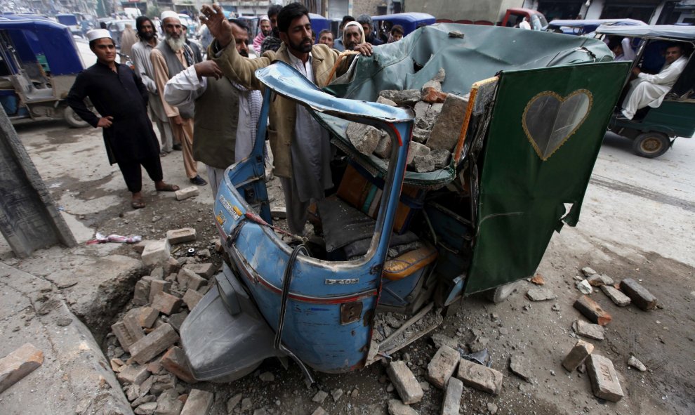 Un hombre retira los escombros caídos sobre su rickshaw.- EFE