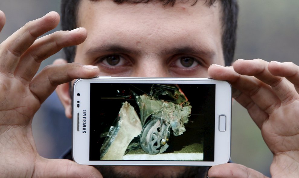 Osman, ciudadanos de Dersol, Siria, muestra una foto de su coche destrozado por los bombardeos de los que huye. Espera cruzar la frontera entre Eslovenia y Austria en Sentilj, Eslovenia.- REUTERS / Srdjan Zivulovic