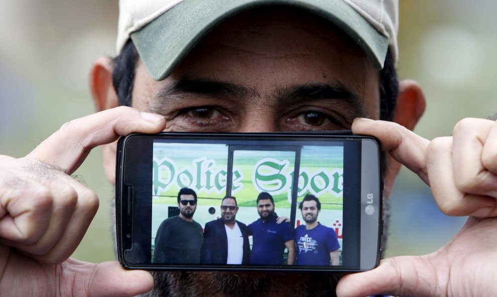 Jabbar, un refugiado procedente de Bagdad, Irak, enseña una foto de sus sobrinos mientras espera para cruzar la frontera entre Eslovenia y Austria en Sentilj, Eslovenia.- REUTERS / Srdjan Zivulovic