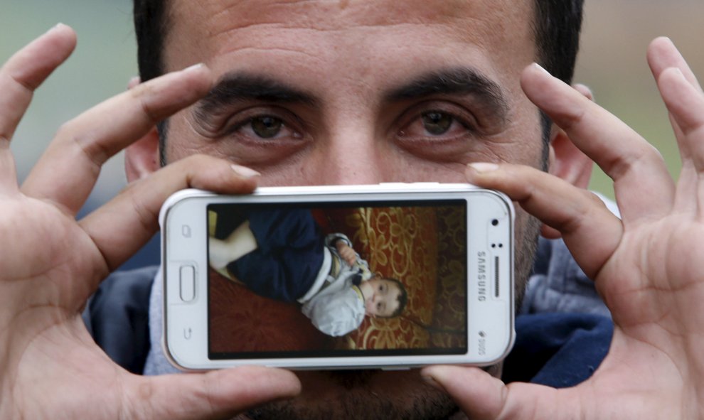Sirad vivía en Zabadani, Siria. En su móvil guarda una foto de su hijo Jad, que observa mientras espera para cruzar la frontera entre Eslovenia y Austria en Sentilj, Eslovenia.- REUTERS / Srdjan Zivulovic