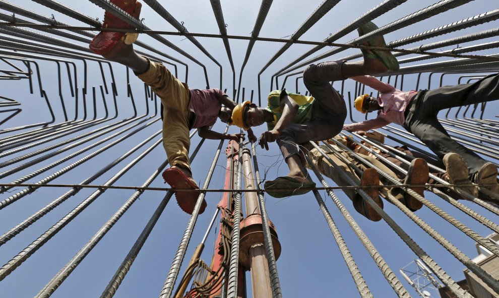 Obreros trabajan en la construcción de un puente de la carretera por encima en Ahmedabad. REUTERS/Amit Dave