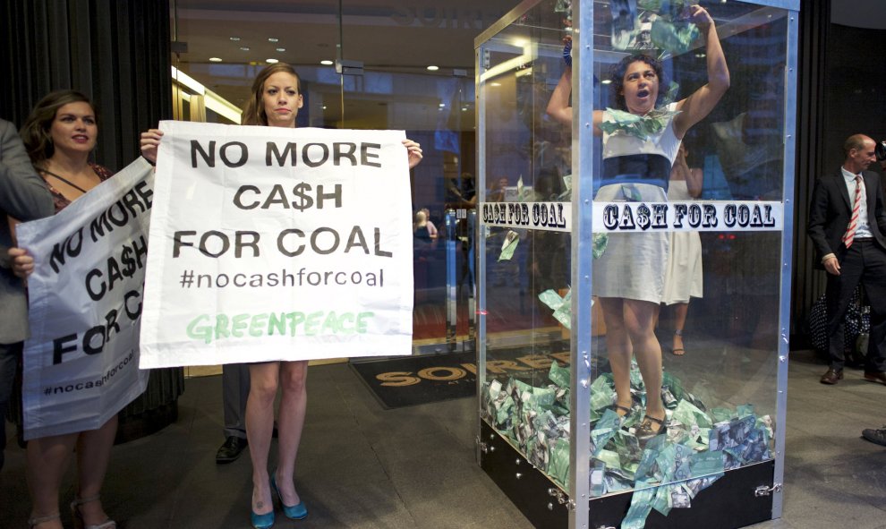 Una manifestante de Greenpeace intenta atrapar el dinero falso en una cabina junto como protesta contra la industria minera de Australia. REUTERS/Jason Reed