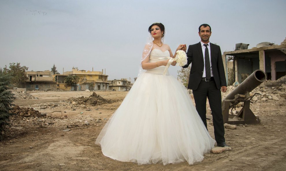 Un novio tiene la mano de su novia, junto a un mortero y edificios dañados antes de dirigirse a su boda en la norteña ciudad siria de Kobani. Esta pareja kurda es la primera en tener un matrimonio civil después que el Estado Islámico capturara la ciudad.-