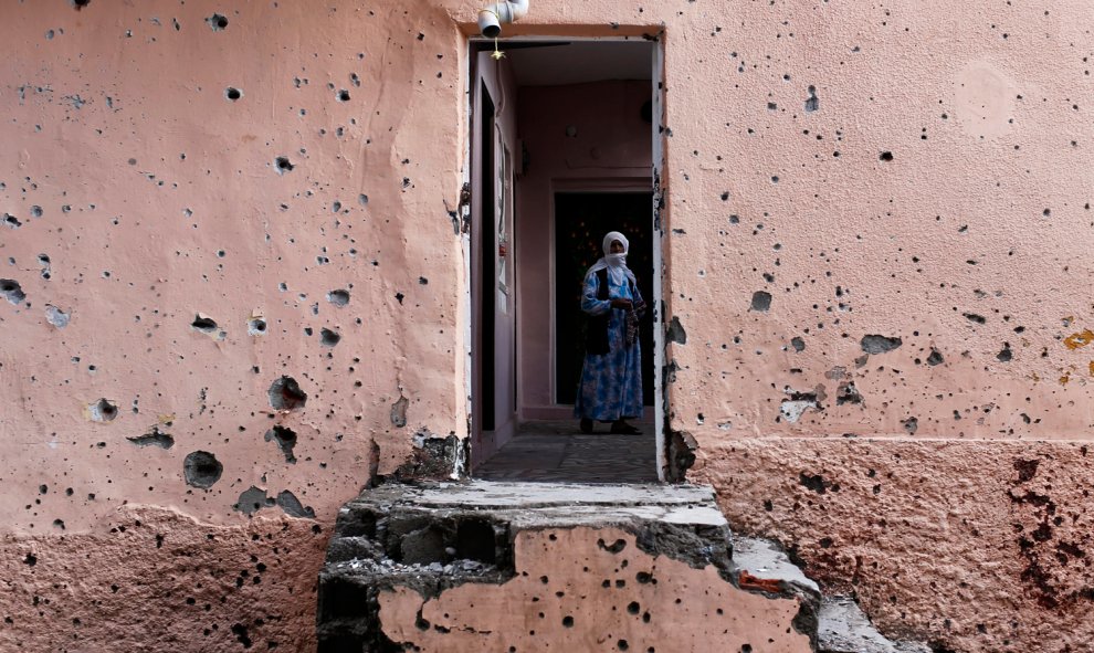 Una mujer kurda mira desde el interior de su casa con la fachada agujereada por los impactos de las balas tras los enfrentamientos entre el ileghalizado Partido de los Trabajadores de Kurdistán (PKK) y las fuerzas turcas, en Diyarbakir (sureste de Turquía