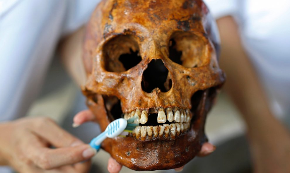 Un voluntario limpia un cráneo de los restos no identificados de una fosa común que están siendo exhumados en el cementerio de la fundación funeraria Poh Teck Tung, en la provincia de Samut Sakhon (Tailandia). Se trata de los restos mortales de más de 3.8