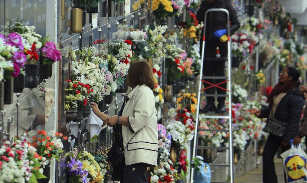 Varias personas limpian y adornan con flores las tumbas de familiares y allegados en el cementerio de Ponferrada, para la celebración del Día de Difuntos que tiene lugar mañana, día 1 de noviembre. EFE/Ana F. Barredo