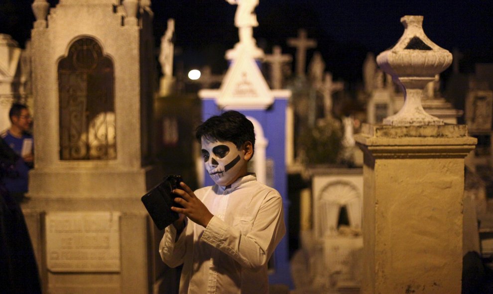 Un niño con la cara pintada de calavera usa su móvil mientras participa en el "Paseo de las Animas" en el día de los difuntos en Mérida, México. REUTERS/Lorenzo Hernandez