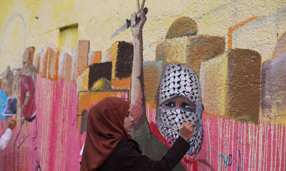 Una mujer palestina pinta un mural en protesta por los ataques israelíes en Rafah al sur de la Franja de Gaza. /REUTERS