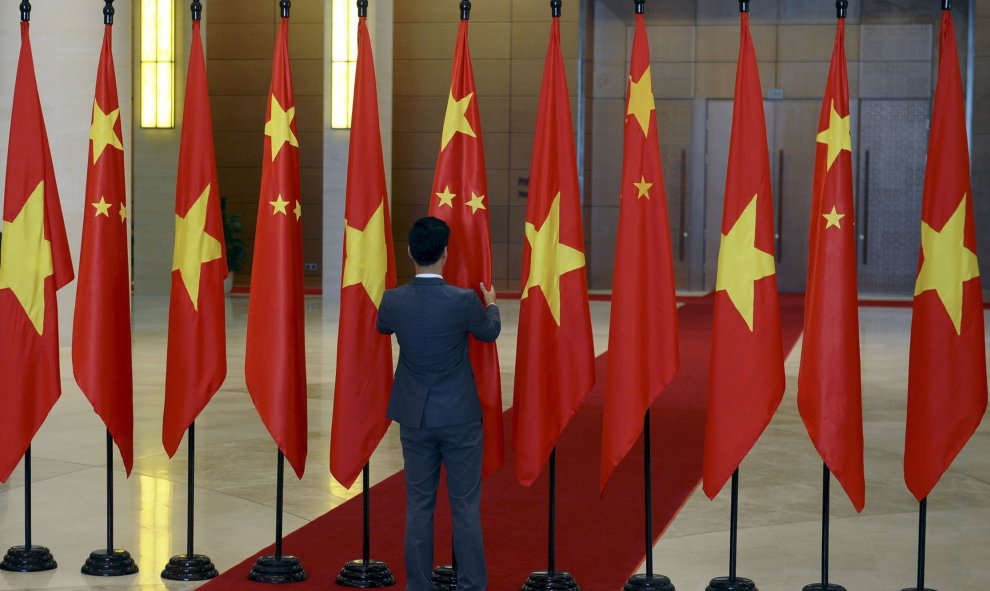 Un oficial de protocolo vietnamita retoca las banderas antes de la llegada del presidente de China, Xi Jinping, a la Casa del Parlamento en Hanoi. REUTERS/Hoang Dinh Nam