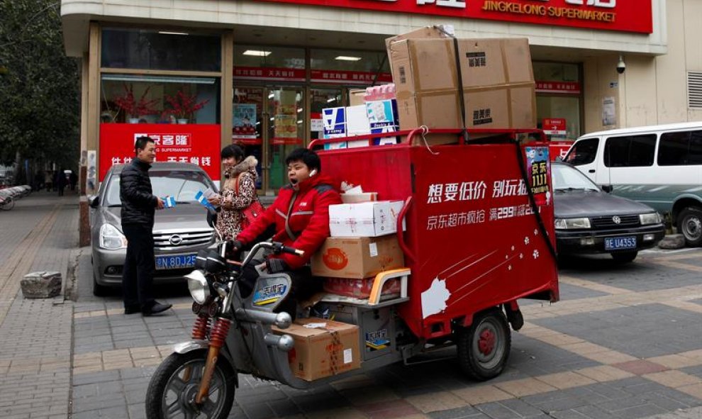 El trabajador de un servicio de mensajería hace su reparto diario en Pekín. EFE
