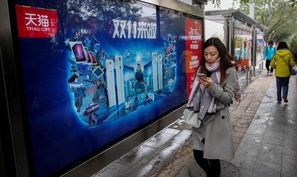 Una mujer pasa por delante de un anuncio publicitario de comercio comercio online en Pekín. EFE