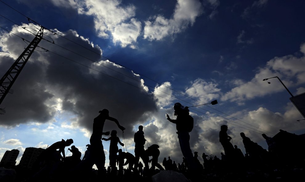 Manifestantes palestinos lanzan piedras durante los disturbios con el ejército israleí en la ciudad cisjordana de Ramala, Palestina hoy con motivo del 11 aniversario de la muerte del histórico líder palestino, Yaser Arafat. EFE/Alaa Badarneh