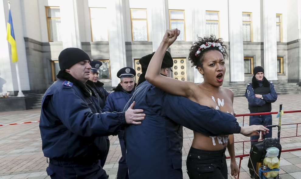 Un policía ucraniano arresta a una activista del movimiento Femen durante una protesta delante del Parlamento en Kiev (Ucrania) contra la homofobia y para reclamar que se corrija el Códido Laboral del país para prevenir y actuar contra la discriminación.
