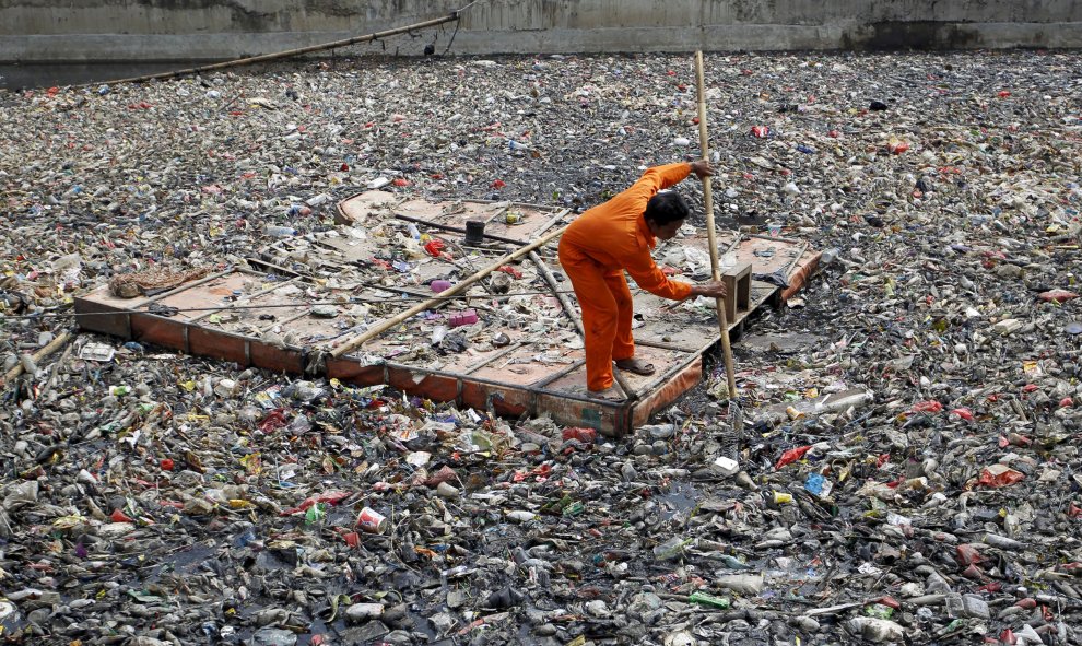 Un trabajador limpia los escombros flotando en el río frente a la temporada de lluvias en el norte de Yakarta, en Indonesia. REUTERS/Garry Lotulung.