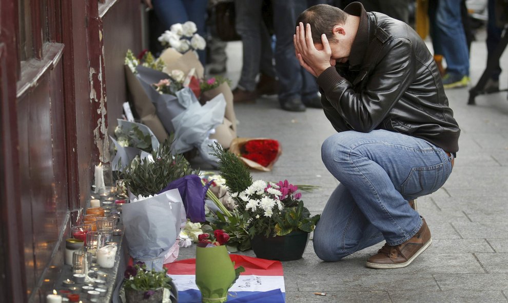 Un hombre se arrodilla en las afueras del restaurante Le Carillon  de París, uno de los objetivos de los ataques de los terroristas. - REUTERS
