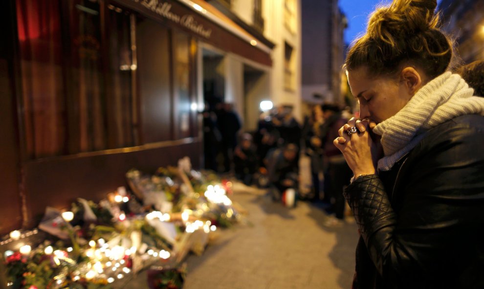 Una mujer muestra sus condolencias a las víctimas en un altar en los alrededores de uno de los lugares de los atentados de París.- REUTERS / Christian Hartman