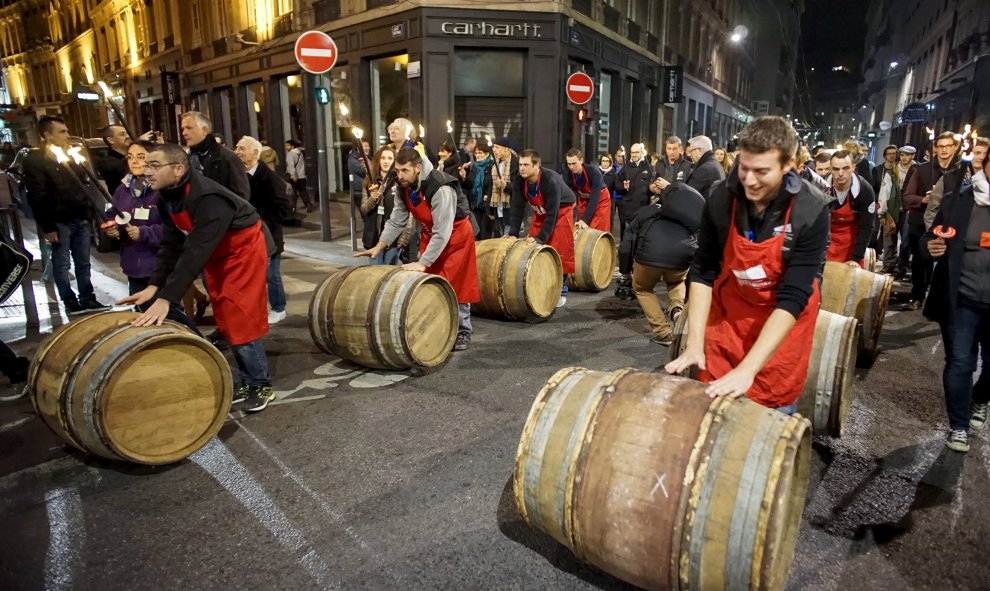 Hombres ruedan barriles de vino Beaujolais Nouveau para el lanzamiento oficial de la vendimia 2015 en el centro de Lyon. REUTERS / Robert Pratta