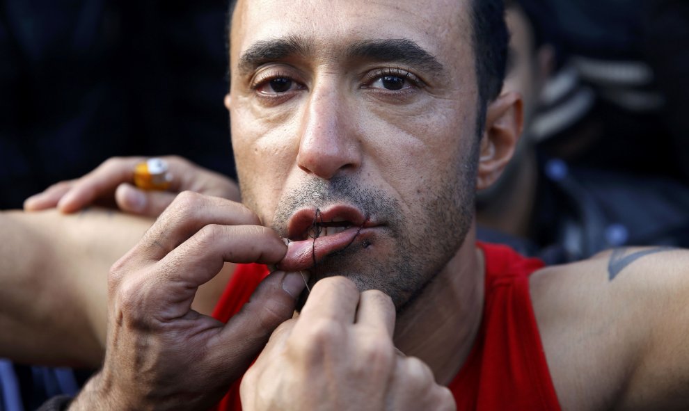 Un inmigrante iraní le cose la boca a otro en una protesta en la frontera cerca de la aldea griega de Idomeni, 26 de noviembre de 2015. REUTERS / Yannis Behrakis