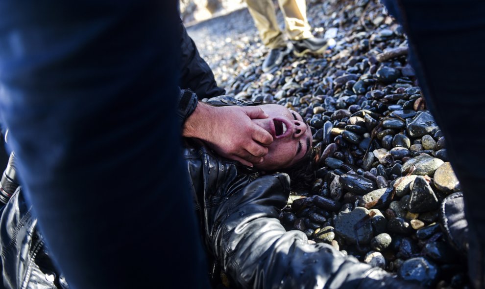 Una mujer herida se encuentra en la orilla después de llegar con otros inmigrantes y refugiados a la isla griega de Lesbos después de haber cruzado el Mar Egeo de Turquía el 26 de noviembre de 2015. AFP / BULENT KILIC